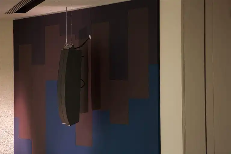 Hanging Innovox Audio speaker against abstract wall design